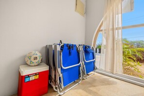 A room with a window, a red cooler, and two blue portable beds.