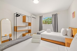 A hotel room with a bed, a bedside table, a mirror, a wardrobe, and a window with curtains.