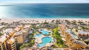 Ein Resort mit mehreren Swimmingpools, einem Strand und Meerblick.