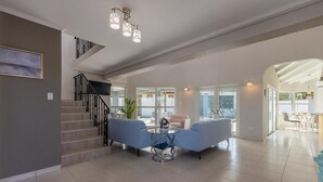 Un vaste espace de vie comprenant un escalier, un coin repas avec une table et des chaises, et une vue sur l’extérieur.