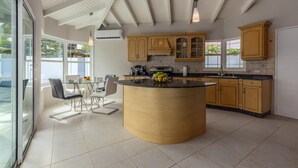 Une cuisine moderne dotée d’un îlot central, de meubles en bois et d’un coin repas avec une table et des chaises en verre.