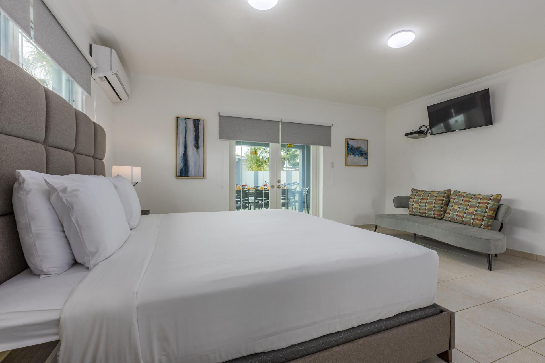 Een moderne slaapkamer met een groot bed, een bank, een televisie en een airconditioner.