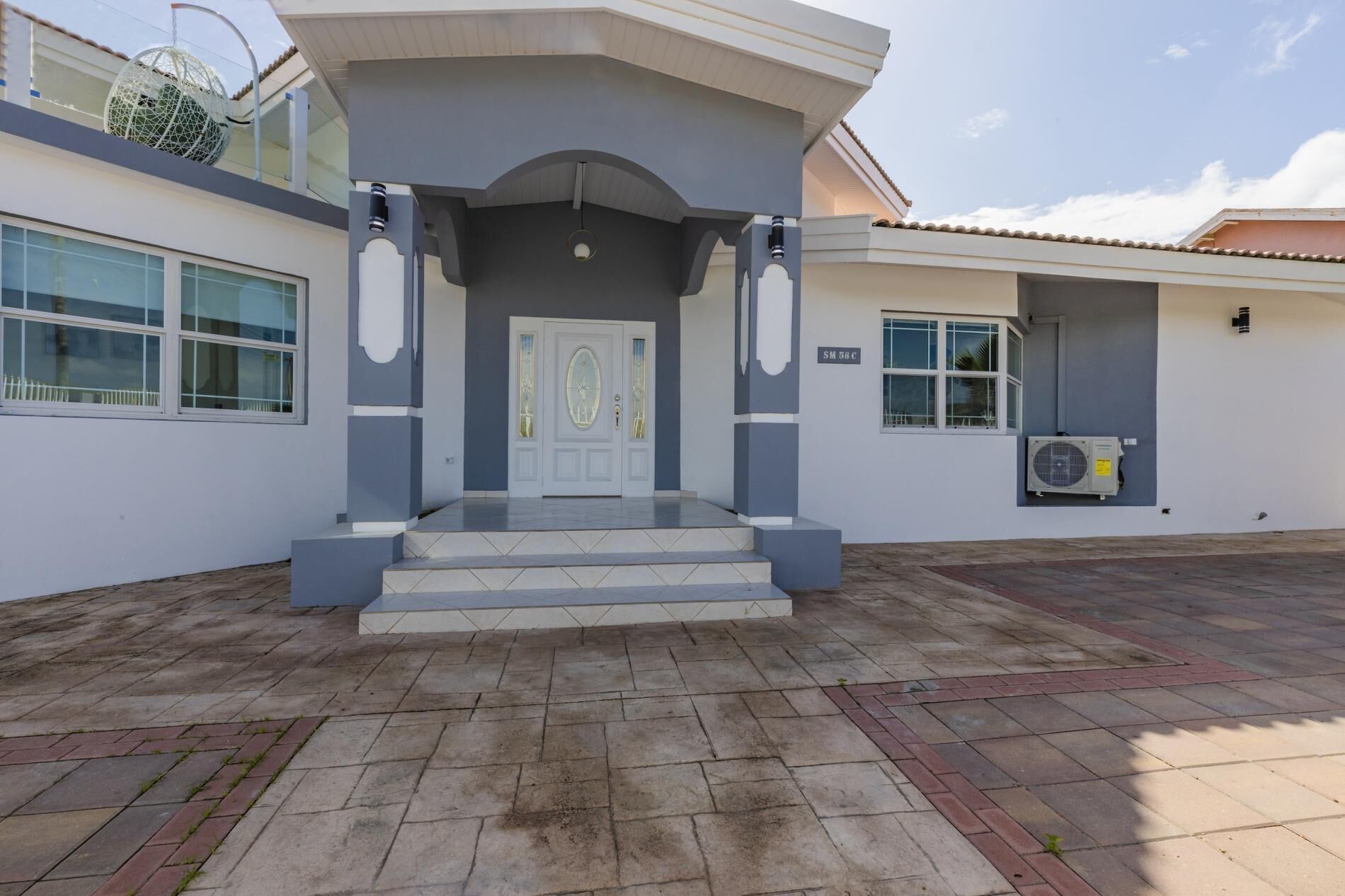 Um edifício moderno com porta branca, paredes cinzentas e entrada revestida com azulejos.