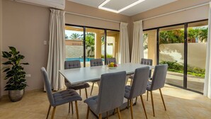 Un comedor moderno con una mesa grande, sillas grises y una planta en maceta.