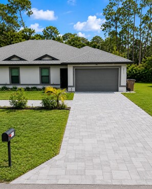 A modern two-story house with a grey roof, a garage, and a well-maintained lawn.