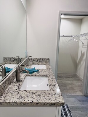 A bathroom with two sinks, a mirror, and a towel rack.