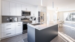 Una cocina moderna con armarios blancos, electrodomésticos de acero inoxidable y una isla grande con fregadero.