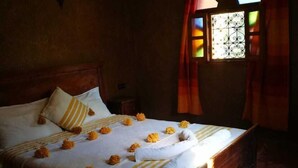 A neatly made bed with a white and yellow striped bedspread, a single pillow, and a decorative headboard. - Guest house in oasis amazrou Zagora south est Maro (Amazraou zagora)