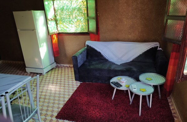 A small room with a sofa, a table, and a red rug. - Guest house in oasis amazrou Zagora south est Maro (Amazraou zagora)