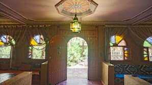 An ornate room with a large wooden door, patterned walls, and a tiled floor. - Guest house in oasis amazrou Zagora south est Maro (Amazraou zagora)
