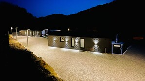 A building with multiple rooms, a gravel driveway, and a mountain backdrop. - Holiday Home 'Voralpen Lodge - Premium' with Jacuzzi, Terrace & Wi-Fi - Adults Only (Traisen)
