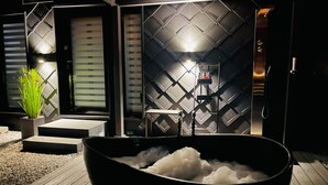 A modern bathroom with a black bathtub, a shower area, and a wall with geometric patterns. - Holiday Home 'Voralpen Lodge - Premium' with Jacuzzi, Terrace & Wi-Fi - Adults Only (Traisen)