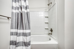 Bathroom features a bathtub, shower curtain, and showerhead.