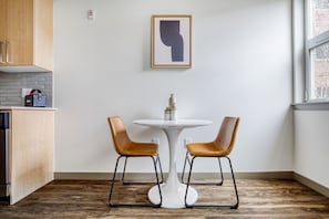 Modern kitchen with a round table and two chairs, an oven, and a window.