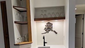 A modern kitchen with a built-in sink, wooden cabinets, and a decorative wall piece above the sink.