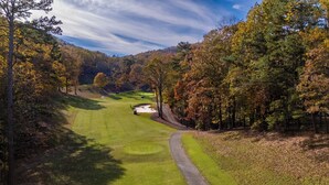 A golf course with a well-maintained green, a winding path, and a backdrop of trees with autumn foliage. - Hiking Trails, Wood-Burning Fireplace & Community Pools - Buckanoe Condo (Jasper)