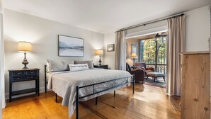 A bedroom with a bed, two bedside tables with lamps, a window with curtains, and a view of the outdoors. - Hiking Trails, Wood-Burning Fireplace & Community Pools - Buckanoe Condo (Jasper)