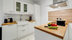 Eine moderne Küche mit weißen Schränken, einer Holz Arbeitsplatte und einer Edelstahl-Dunstabzugshaube.