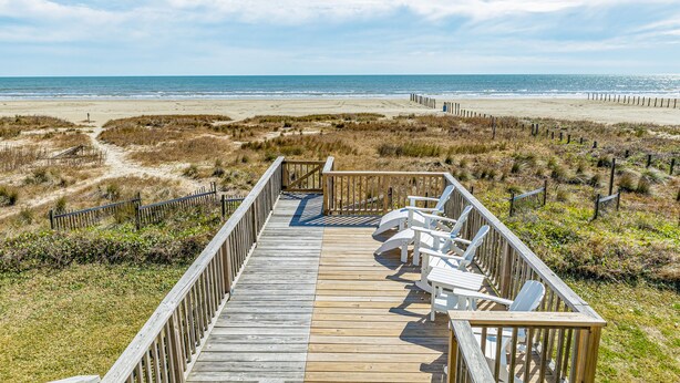 A wooden boardwalk leading to beach chairs overlooking the ocean. - Beachfront home with beach access, deck, outdoor shower & washer/dryer (Galveston)