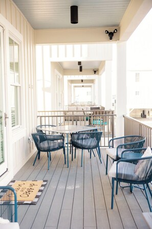 A covered outdoor area with a table and chairs, a doormat, and a view of the interior. - Driftwood Haus - Steps to Beach - 7 Separate Beds - Pet Friendly - Pool - Grill (Gulf Shores)