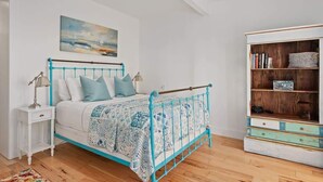 Ein Schlafzimmer mit Bett, Nachttisch, Lampe und Bücherregal.