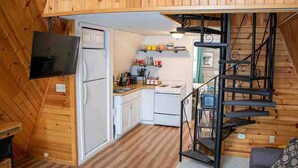 A compact kitchen with a refrigerator, stove, and sink, a small dining area, and a staircase leading to an upper level. - A-frame, Fireplace,Private Lake Lot, Dock, Kayaks. (Alexandria)