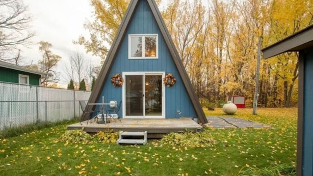 A blue triangular house with a front porch and a sliding glass door. - A-frame, Fireplace,Private Lake Lot, Dock, Kayaks. (Alexandria)