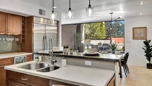 Una cucina moderna con elettrodomestici in acciaio inossidabile, un lavello doppio e luci a sospensione.