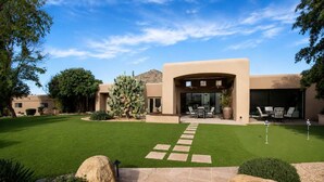 Una casa moderna con un patio, un cactus e un cielo sereno.