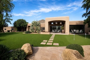Una casa moderna con un patio, un cactus y cielo despejado.