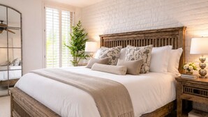 Una camera da letto con un letto grande, una testiera in legno, un comodino con una lampada e uno specchio.