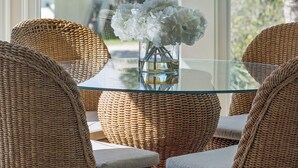 A glass-top table with wicker chairs and a vase of white flowers. - The Sanctuary -Premier Oceanfront Rental -Large Decks, Pet Friendly! (Folly Beach)