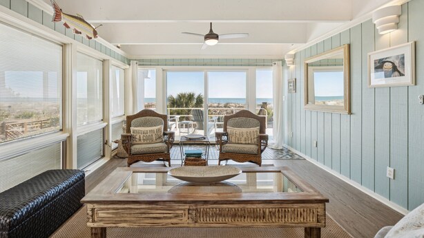 A sunlit room with a large window, a ceiling fan, and a view of the ocean. - The Sanctuary -Premier Oceanfront Rental -Large Decks, Pet Friendly! (Folly Beach)