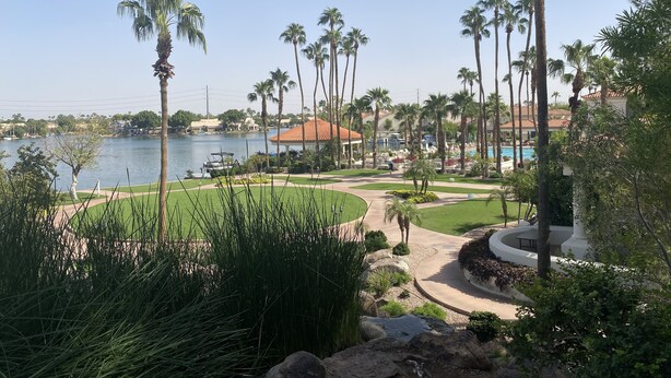 Un resort con vista al lago, palmeras y una piscina.