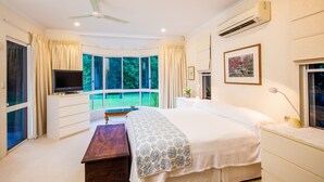 A bedroom with a large bed, a TV, a desk, and a window with curtains. - Luxury Home in Nature surrounded by Wallabies (Clifton Beach)