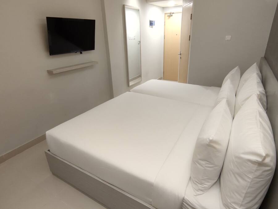 A hotel room with a bed, a television mounted on the wall, and a door leading to a bathroom.