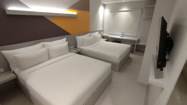 A modern hotel room with two beds, a bedside table, a mirror, a TV, and a bathroom with a sink and mirror. - Agogo Downtown (Surabaya)