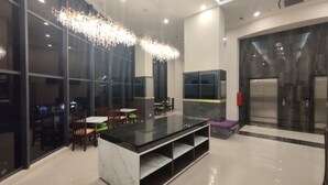 A modern interior with a central black marble island, wooden chairs with green cushions, and a hanging light fixture. - Agogo Downtown (Surabaya)