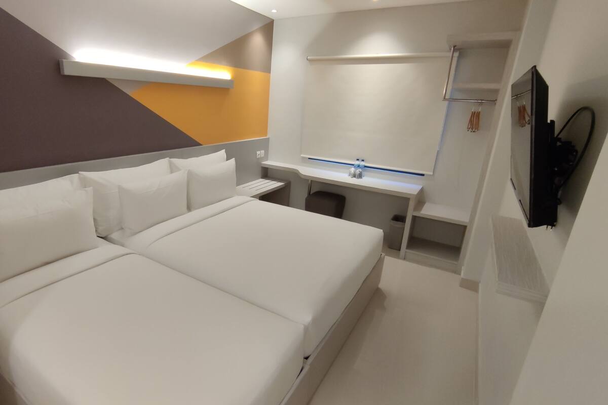 A modern hotel room with a large bed, bedside tables, a desk, and a shower area.