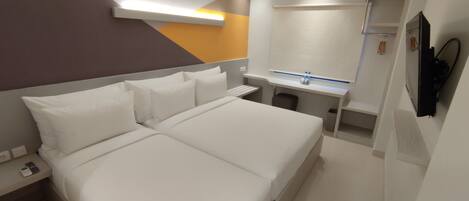 A modern hotel room with a large bed, a desk, a shower, and a TV.
