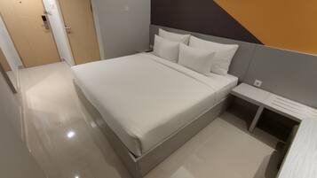 A modern hotel room with a large bed, a bedside table, and a nightstand.