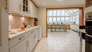 Una cocina moderna con armarios blancos, un comedor con un ventanal y vistas al exterior.