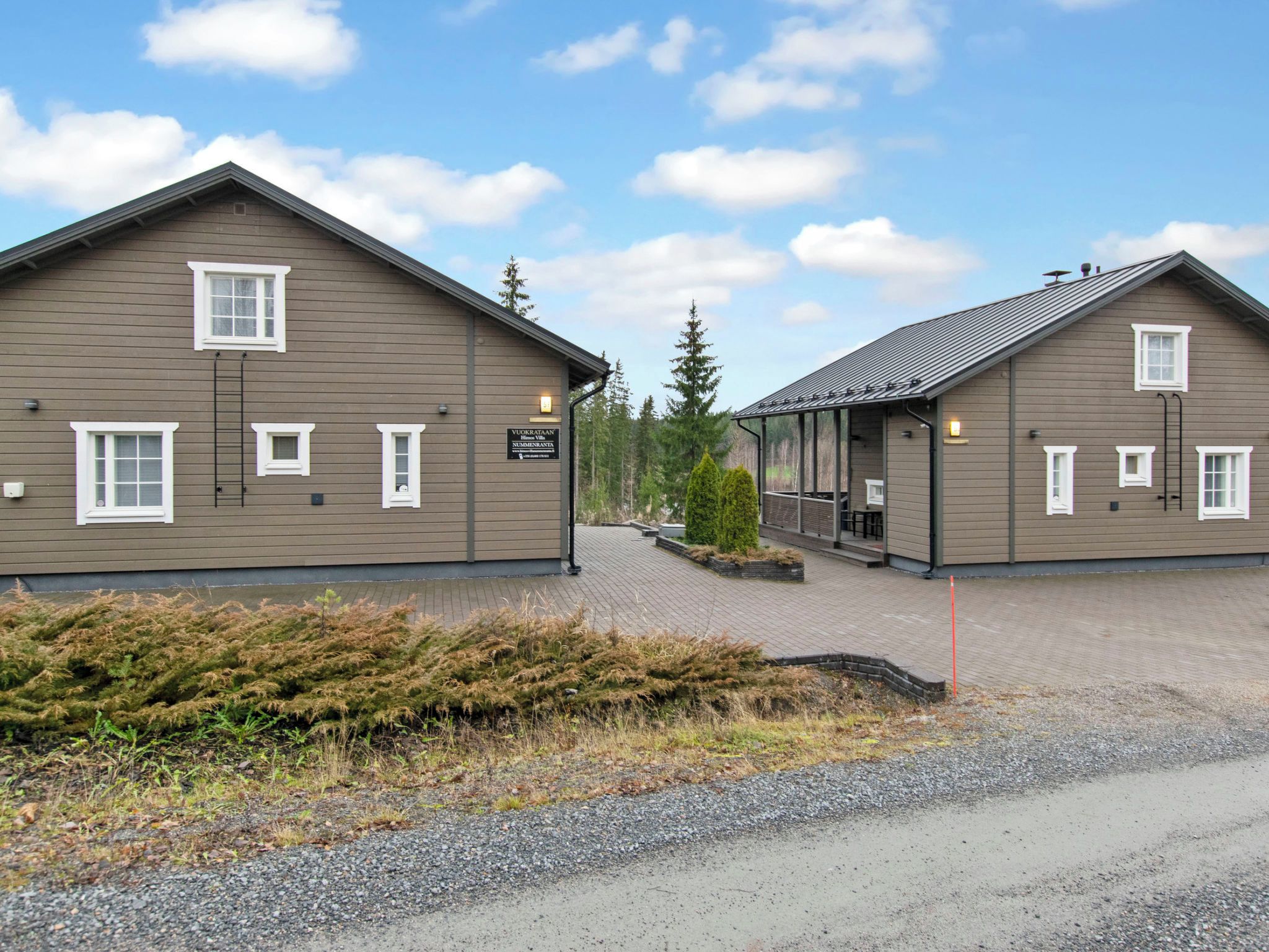 Two large, single-story buildings with a flat roof, a covered walkway, and a gravel driveway.