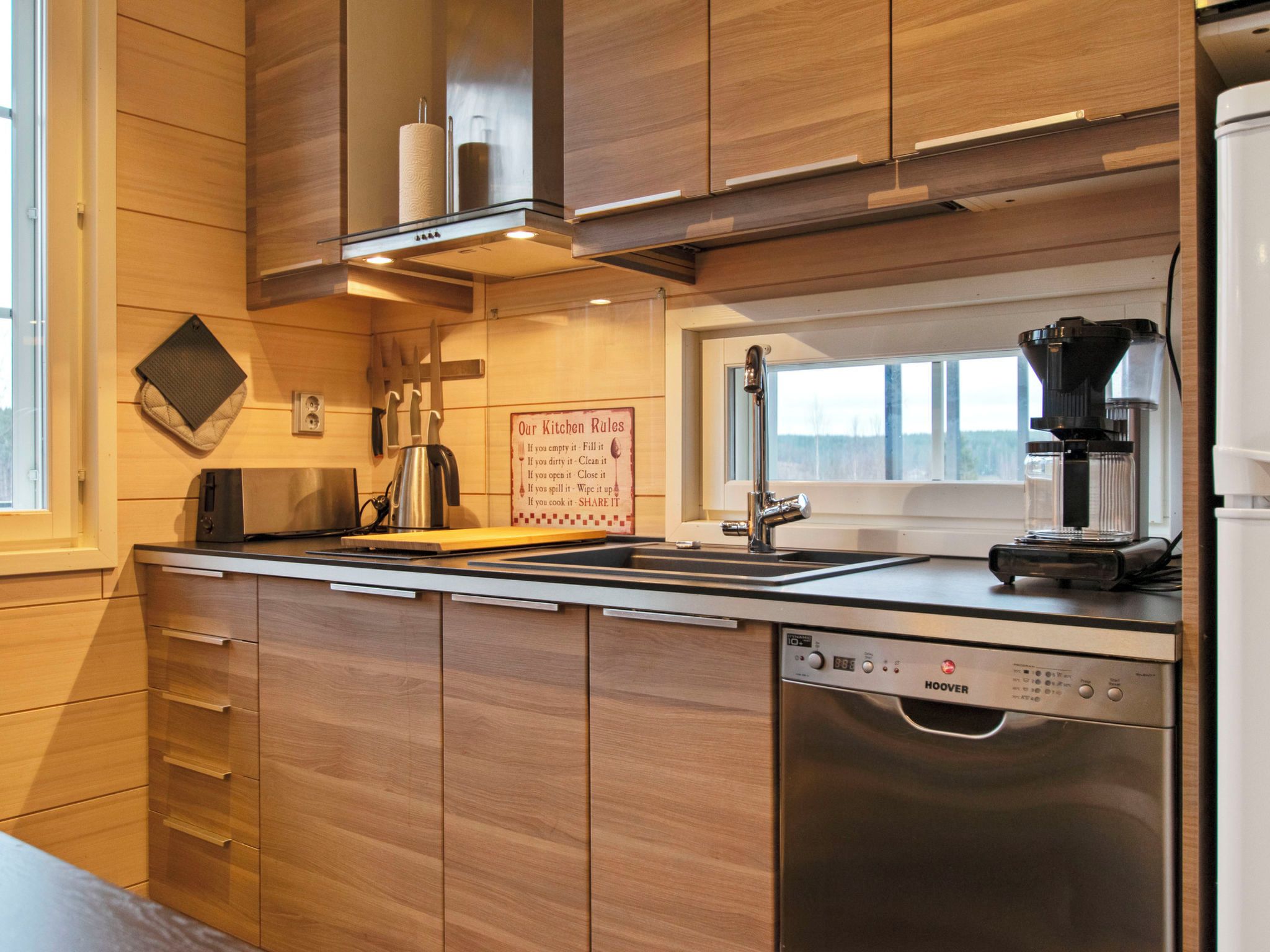 A modern kitchen with wooden cabinets, stainless steel appliances, and a coffee machine.