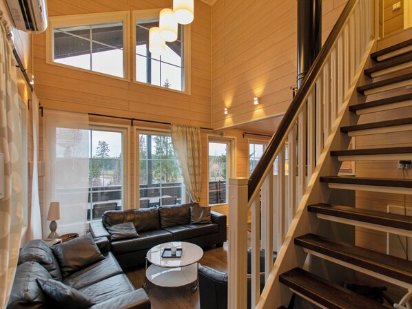 A spacious living area with a modern staircase, large windows, and a leather sofa.