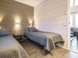 A modern room with two beds, wooden walls, and built-in lighting.