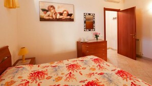 Een slaapkamer met een bed, een dressoir, een spiegel en een deur.