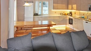 A modern kitchen with wooden cabinets, a central island, and a dining table. - Villa lahti by Interhome (Leppävirta)