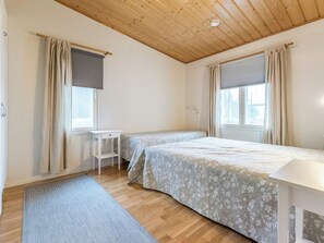 Ein Schlafzimmer mit zwei Betten, einem Schreibtisch und einem fenster mit Vorhängen.