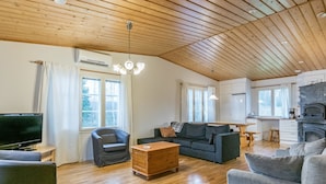 A spacious living area with a wooden ceiling, a television, a sofa, a coffee table, and a fireplace. - Villa lahti by Interhome (Leppävirta)
